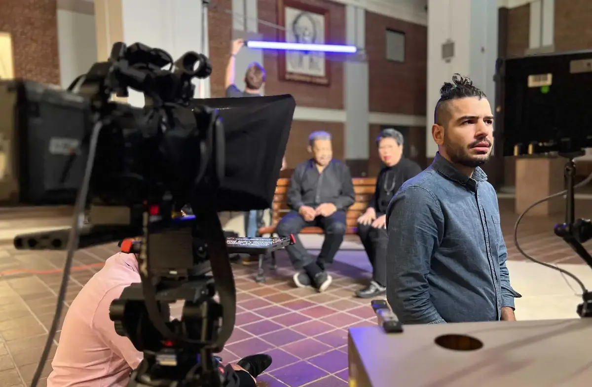 Javier filming a documentary interview with two subjects seated on a bench
