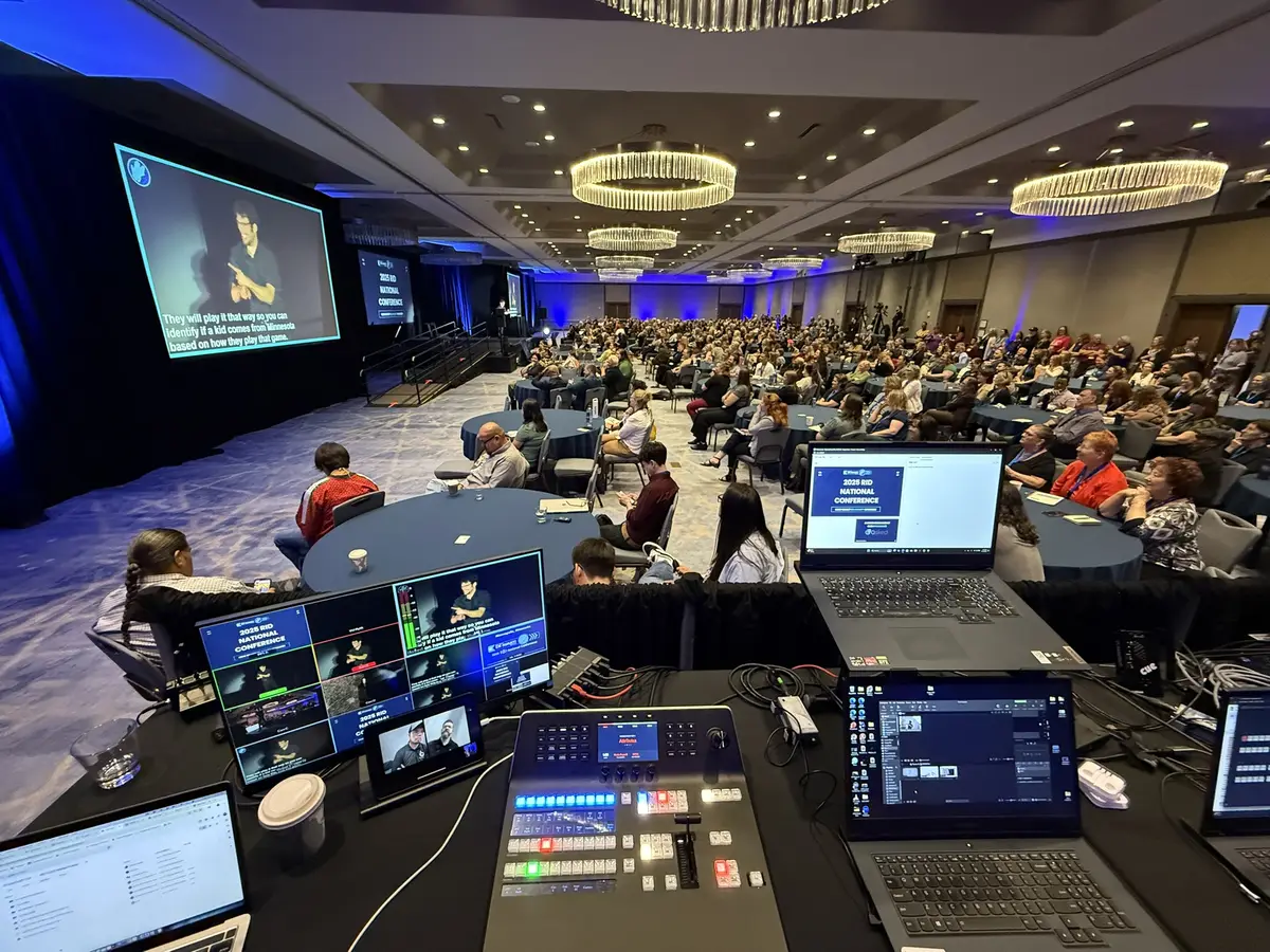 Wide view of the ballroom and audience at the RID National Conference with ASL interpretation on screen